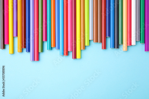 Colorful wooden pencils on light blue background, flat lay. Space for text