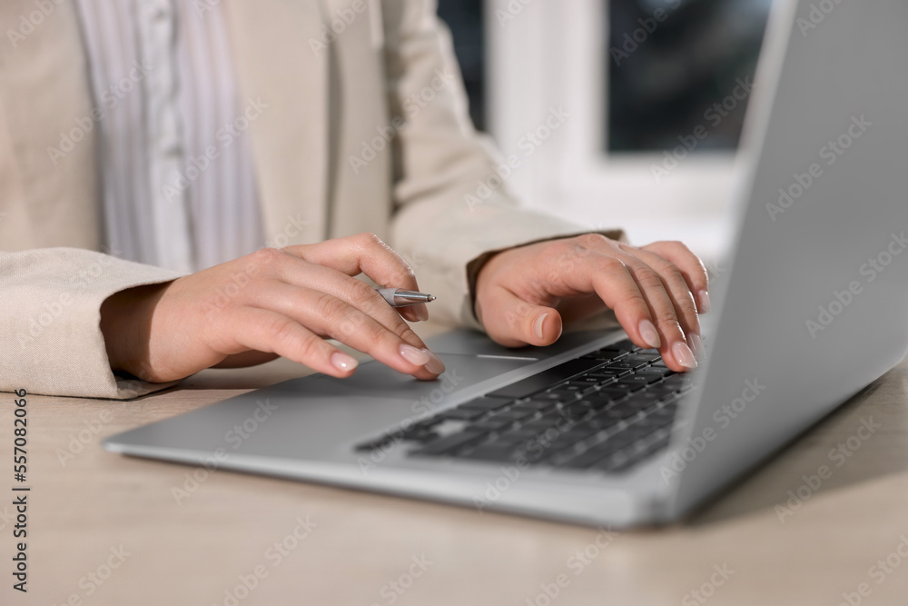 Woman with pen working on laptop at wooden table, closeup. Electronic document management Woman with pen working on laptop at wooden table, closeup. Electronic document management