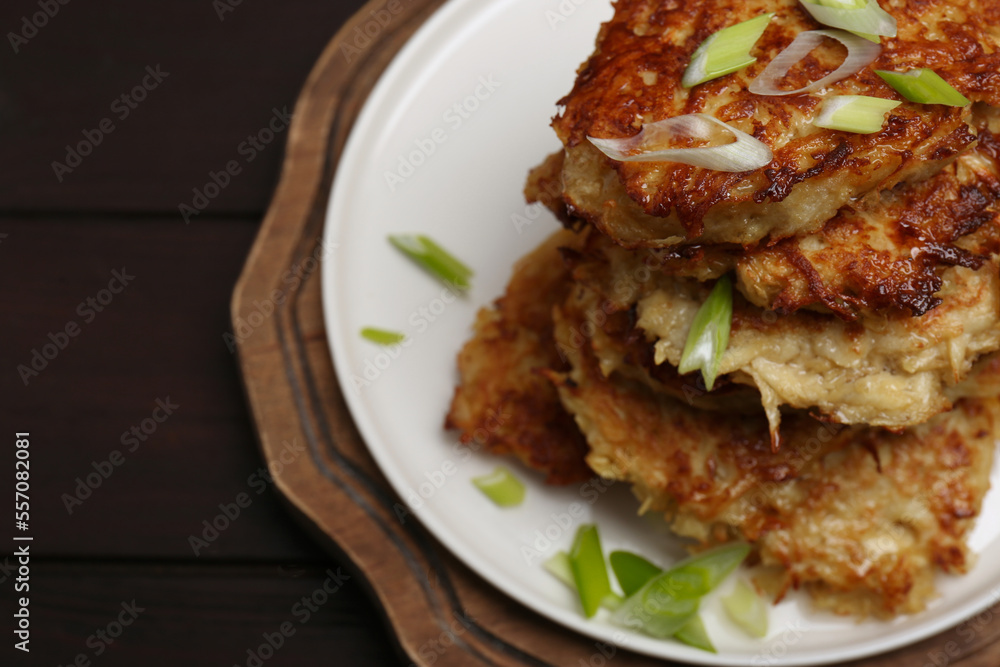 Tasty parsnip cutlets with green onion on wooden table, closeup