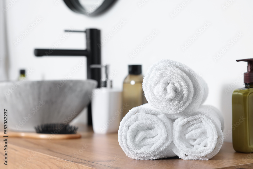 Rolled bath towels on wooden table in bathroom. Space for text Rolled bath towels on wooden table in bathroom. Space for text
