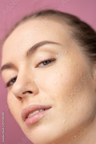 Girl's face with water drops on her face Looks at the camera Blue eyes Close up Horizontal frame Purple background Beauty ,Cosmeics,Fashion Open mouth