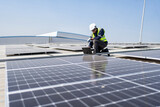 Engineer on rooftop kneeling next to solar panels photo voltaic with tool in hand for installation