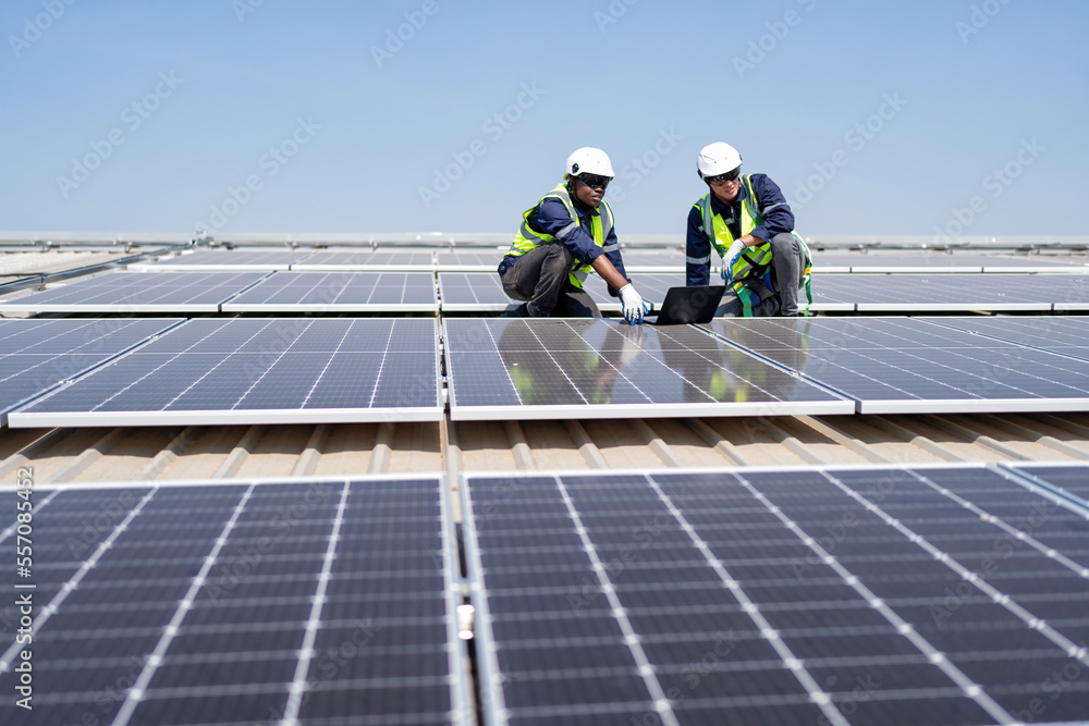 Engineer on rooftop kneeling next to solar panels photo voltaic check laptop for good installation Engineer on rooftop kneeling next to solar panels photo voltaic check laptop for good installation