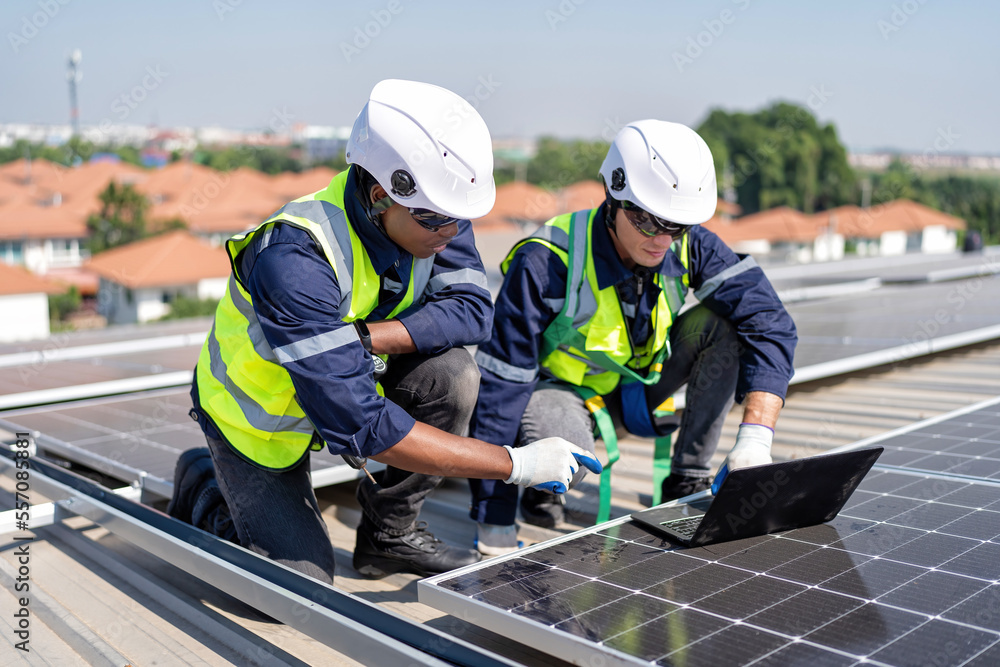 Engineer on rooftop kneeling next to solar panels photo voltaic check laptop for good installation Engineer on rooftop kneeling next to solar panels photo voltaic check laptop for good installation