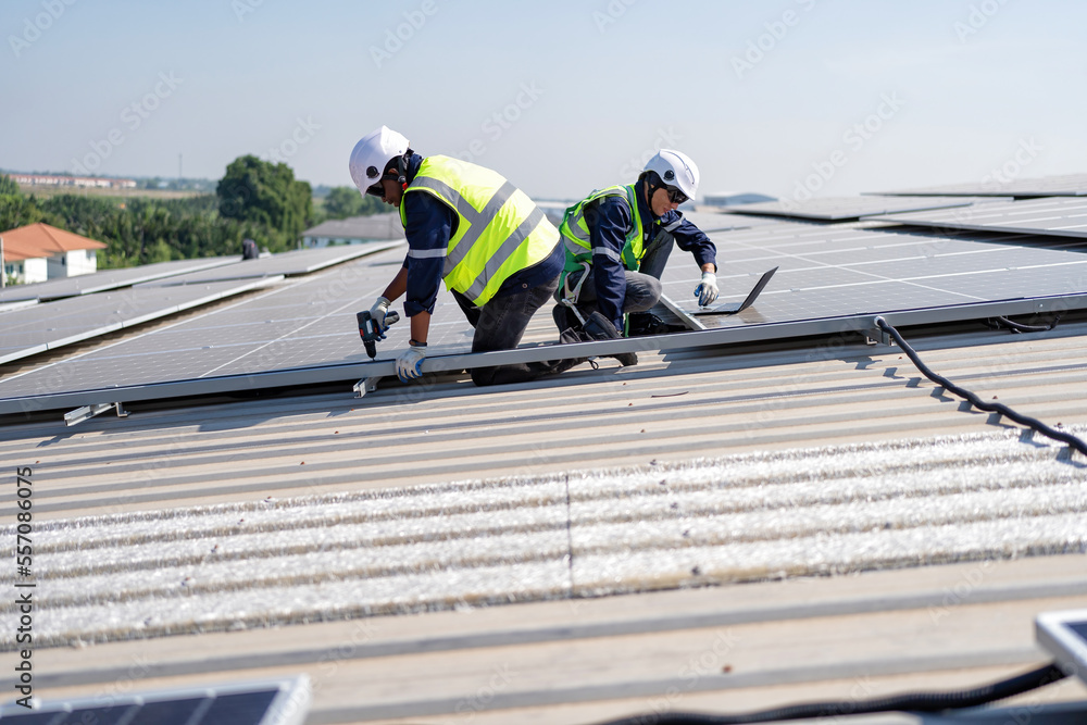 Engineer on rooftop kneeling next to solar panels photo voltaic check laptop for good installation Engineer on rooftop kneeling next to solar panels photo voltaic check laptop for good installation