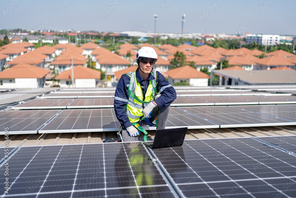 Engineer on rooftop kneeling next to solar panels photo voltaic check laptop for good installation Engineer on rooftop kneeling next to solar panels photo voltaic check laptop for good installation