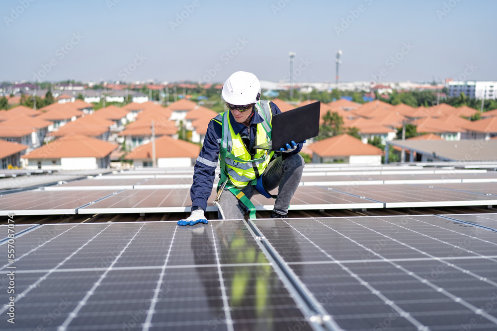 Engineer on rooftop kneeling next to solar panels photo voltaic with tool in hand for installation Engineer on rooftop kneeling next to solar panels photo voltaic with tool in hand for installation
