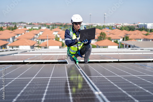 Engineer on rooftop kneeling next to solar panels photo voltaic check laptop for good installation