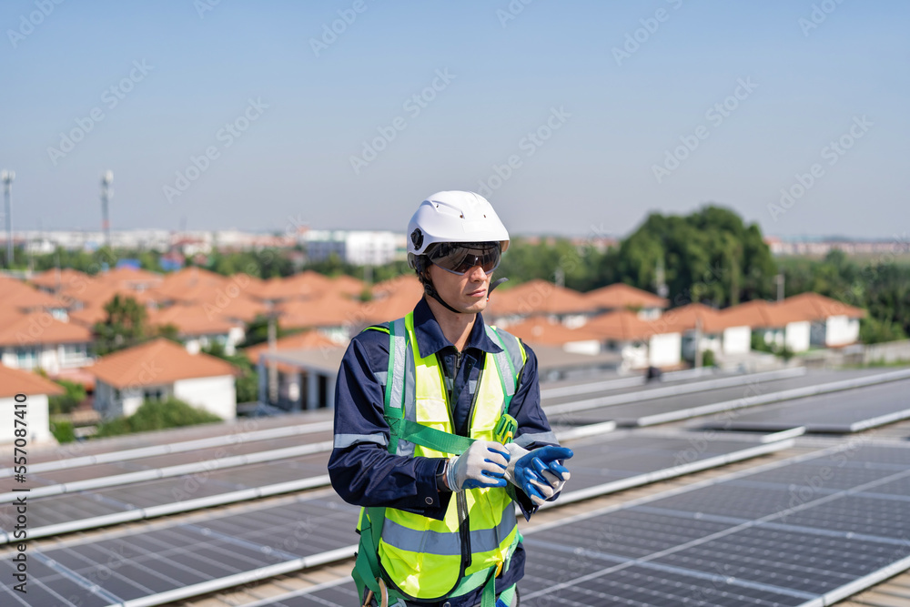 Obraz premium Engineer on rooftop stand next to solar panels wear safety gear wear hand gloves ready to work