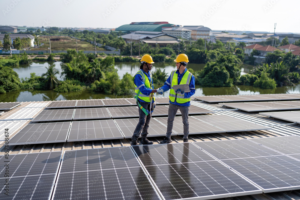 Engineer on rooftop stand next to solar panels discussion with team check laptop for installation Engineer on rooftop stand next to solar panels discussion with team check laptop for installation