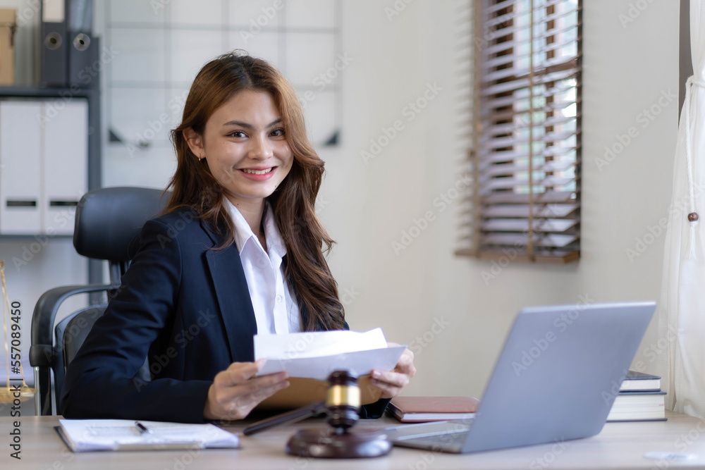 Attractive young lawyer in office Business woman and lawyers discussing contract papers with brass scale on wooden desk in office. Law, legal services, advice, Justice and real estate concept. Attractive young lawyer in office Business woman and lawyers discussing contract papers with brass scale on wooden desk in office. Law, legal services, advice, Justice and real estate concept.