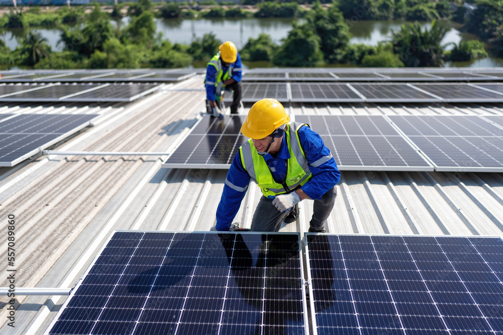 Engineer on rooftop kneeling next to solar panels photo voltaic with tool in hand for installation Engineer on rooftop kneeling next to solar panels photo voltaic with tool in hand for installation