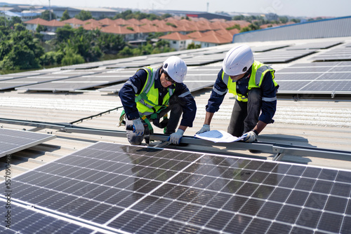Engineer on rooftop kneeling next to solar panels photo voltaic check drawing for good installation
