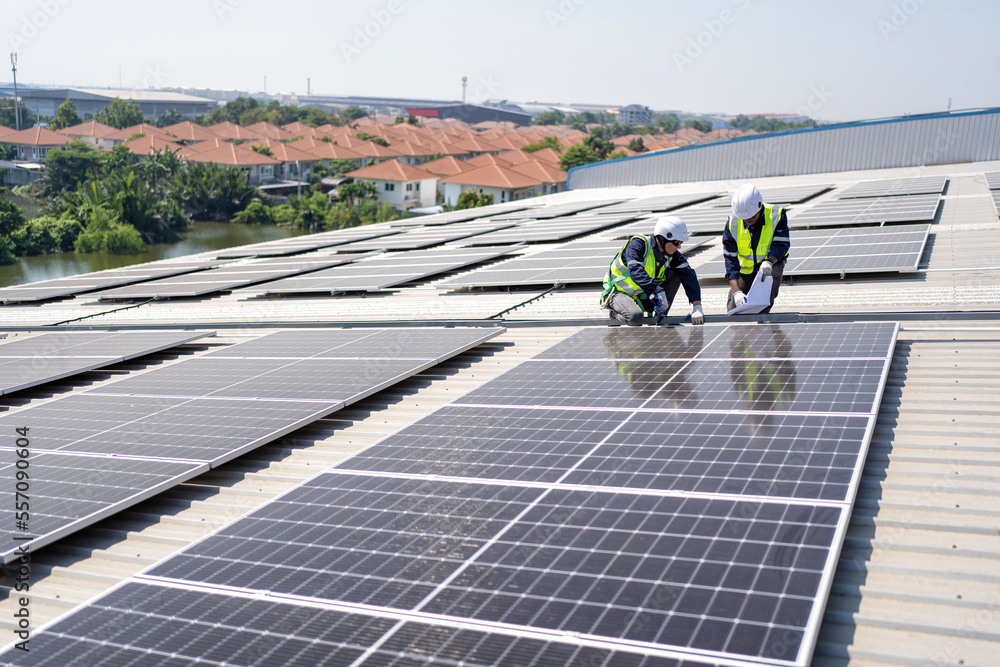 Engineer on rooftop kneeling next to solar panels photo voltaic with tool in hand for installation Engineer on rooftop kneeling next to solar panels photo voltaic with tool in hand for installation