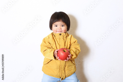 りんごを持った女の子。おかっぱヘアーの二歳児。