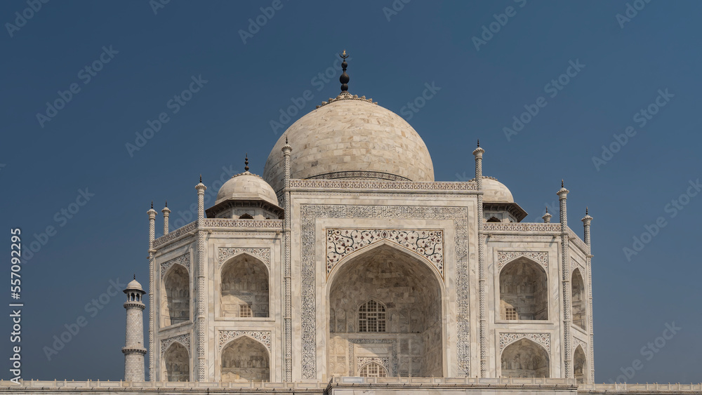 Beautiful majestic Taj Mahal against the blue sky. The white marble ancient mausoleum with domes, arches, spires decorated with inlays of precious stones, ornaments. India. Agra.