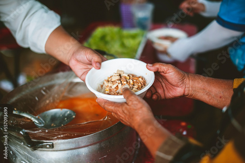 Volunteer's hands offer shared food to the poor to alleviate hunger : humanitarian aid concept.