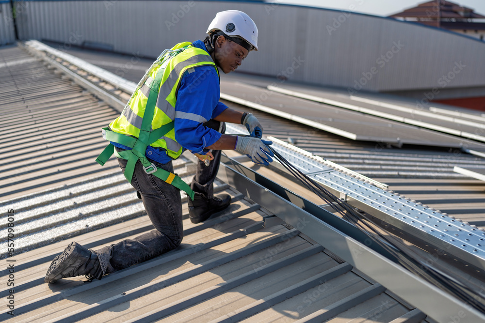 Engineer on rooftop knee down check cable pulling for solar panels photo voltaic installation Engineer on rooftop knee down check cable pulling for solar panels photo voltaic installation