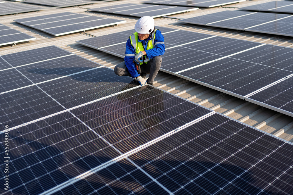 Engineer on rooftop kneeling next to solar panels photo voltaic with tool in hand for installation Engineer on rooftop kneeling next to solar panels photo voltaic with tool in hand for installation