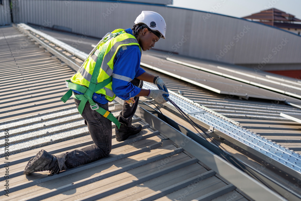Engineer on rooftop knee down check cable pulling for solar panels photo voltaic installation Engineer on rooftop knee down check cable pulling for solar panels photo voltaic installation
