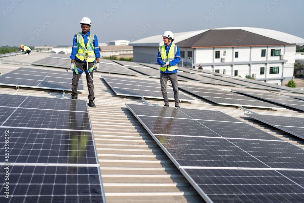 Engineer on rooftop sitting next to solar panels photo voltaic check alignment for good installation Engineer on rooftop sitting next to solar panels photo voltaic check alignment for good installation