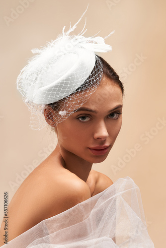 Obraz na plátne Cropped close-up shot of a young woman in a white felt pillbox hat with a veil decorated with feathers