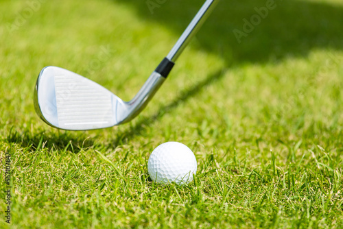 Close-up of the white golf ball on a stand on a green field