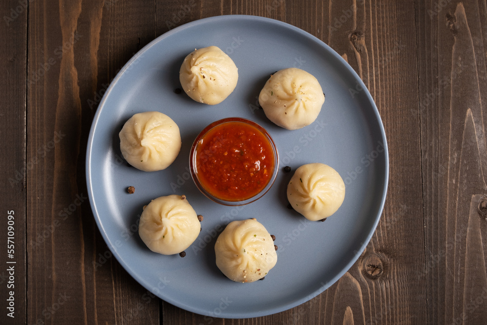 Khinkali on a blue plate with spicy tomato sauce. Dish of Georgian cuisine. Khinkali on a blue plate with spicy tomato sauce. Dish of Georgian cuisine.