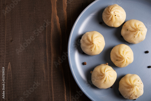 Khinkali on a blue plate on a wooden background with space for text.
