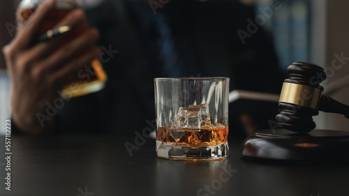 A lawyer holding a glass of whiskey  He s in his office  and he s stressing about arguing for a client  he s a lawyer. The concept of clear legal litigation.