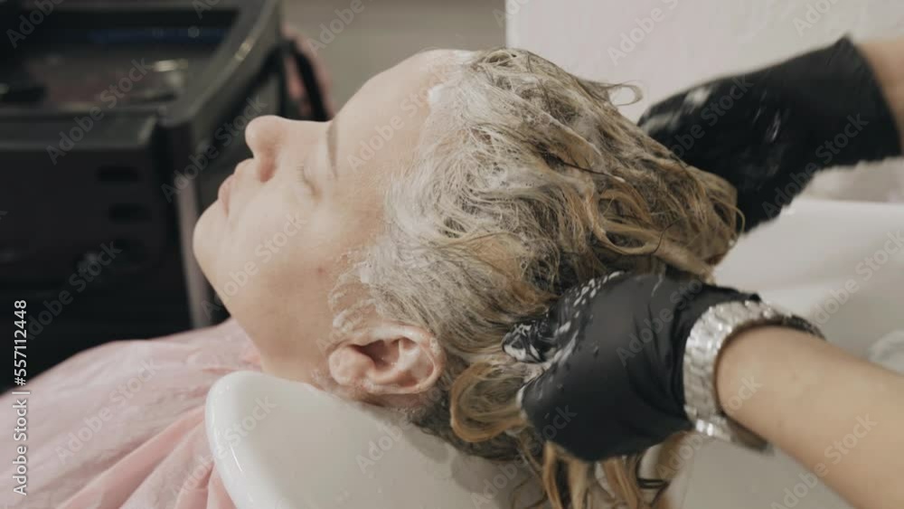 A woman hairdresser washes woman's hair after dyeing her hair. Close-up A woman hairdresser washes woman's hair after dyeing her hair. Close-up