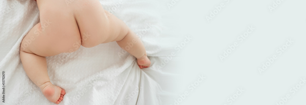 Baby butts. Baby is lying on bed waiting for pediatric massage oil. Top view. Copy space for advertisement.
