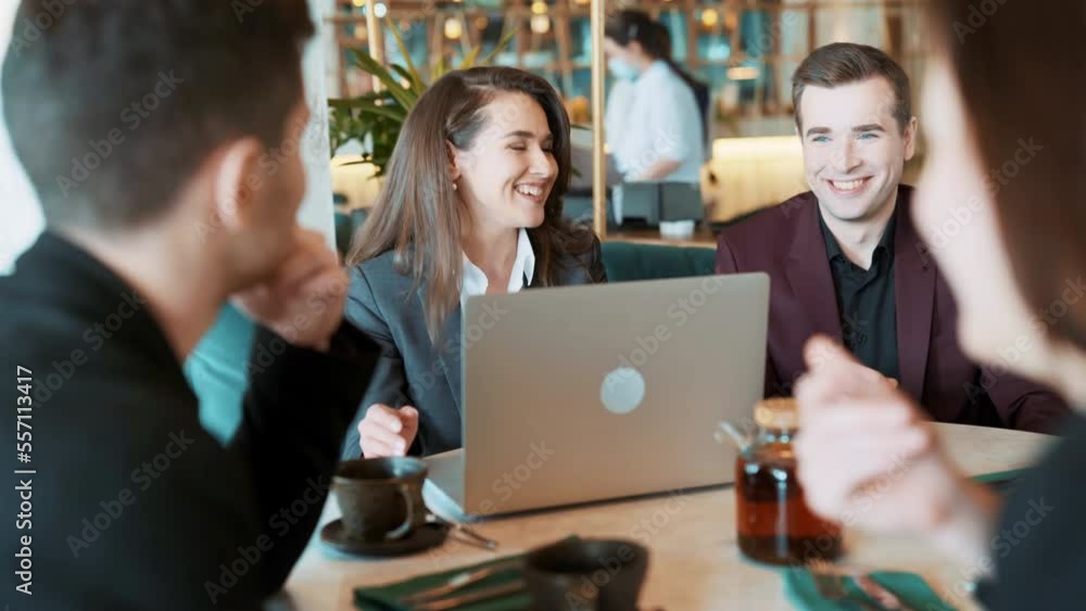 Group of suit wearing colleagues discussing working situation sitting at table in cafe with laptop. Casual coworkers having sparkling conversation in reastaurant. Concept of teambuilding, leisure. Group of suit wearing colleagues discussing working situation sitting at table in cafe with laptop. Casual coworkers having sparkling conversation in reastaurant. Concept of teambuilding, leisure.