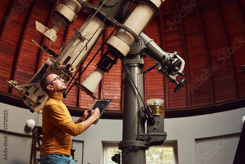 Astronomer with a big astronomical telescope in observatory doing science research. photo