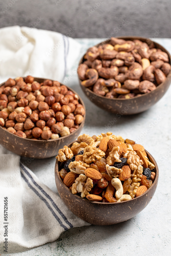 assortment of nuts on a gray background. Hazelnuts, walnuts and mixed nuts in a coconut bowl. close up assortment of nuts on a gray background. Hazelnuts, walnuts and mixed nuts in a coconut bowl. close up