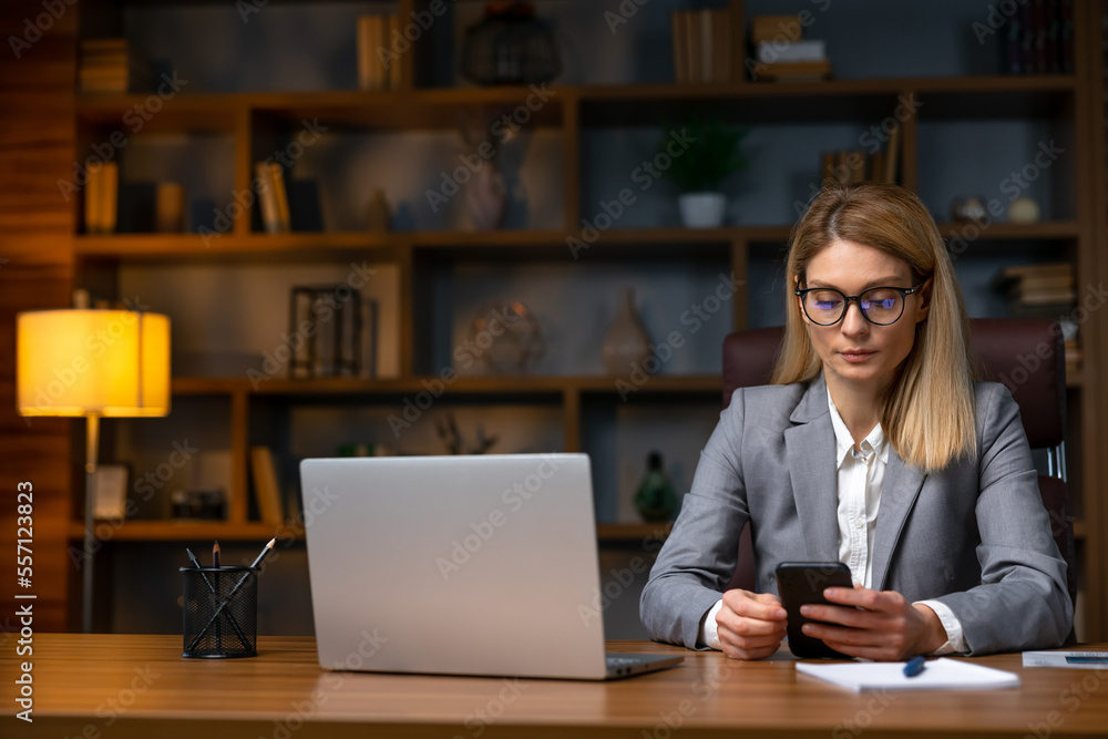 Woman uses smartphone in office. A beautiful girl is looking at Woman uses smartphone in office. A beautiful girl is looking at