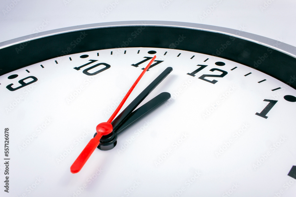 Midnight is coming. Black and white office clock with a red pointer on a gray background. Midnight is coming. Black and white office clock with a red pointer on a gray background.