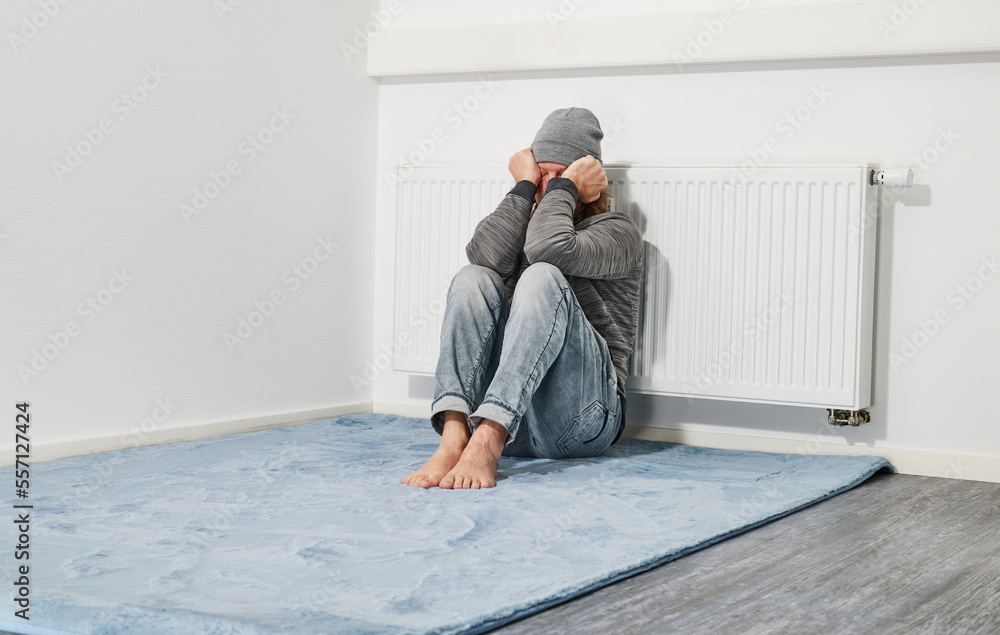 Man freezing in front of heating radiator Man freezing in front of heating radiator