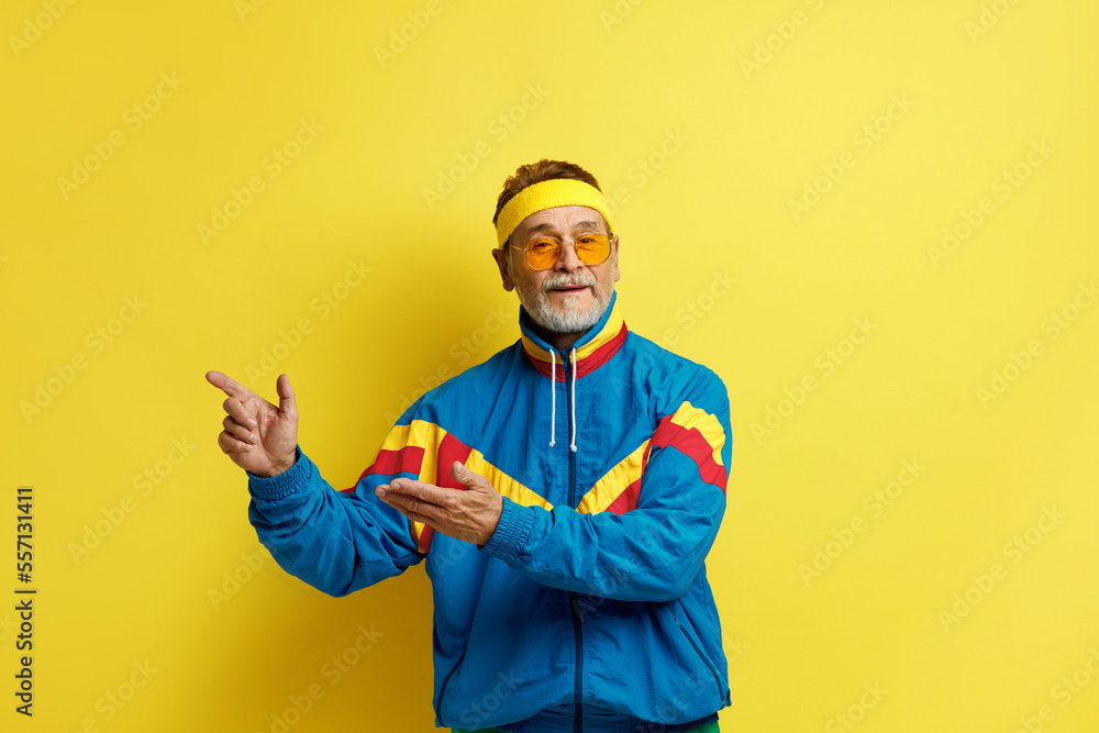 Man Pointing Hand. Positive Mature Man Pointing Away Paying Your Attention at Empty Space for Advertisement. Indoor Studio Shot Isolated on Yellow Background 