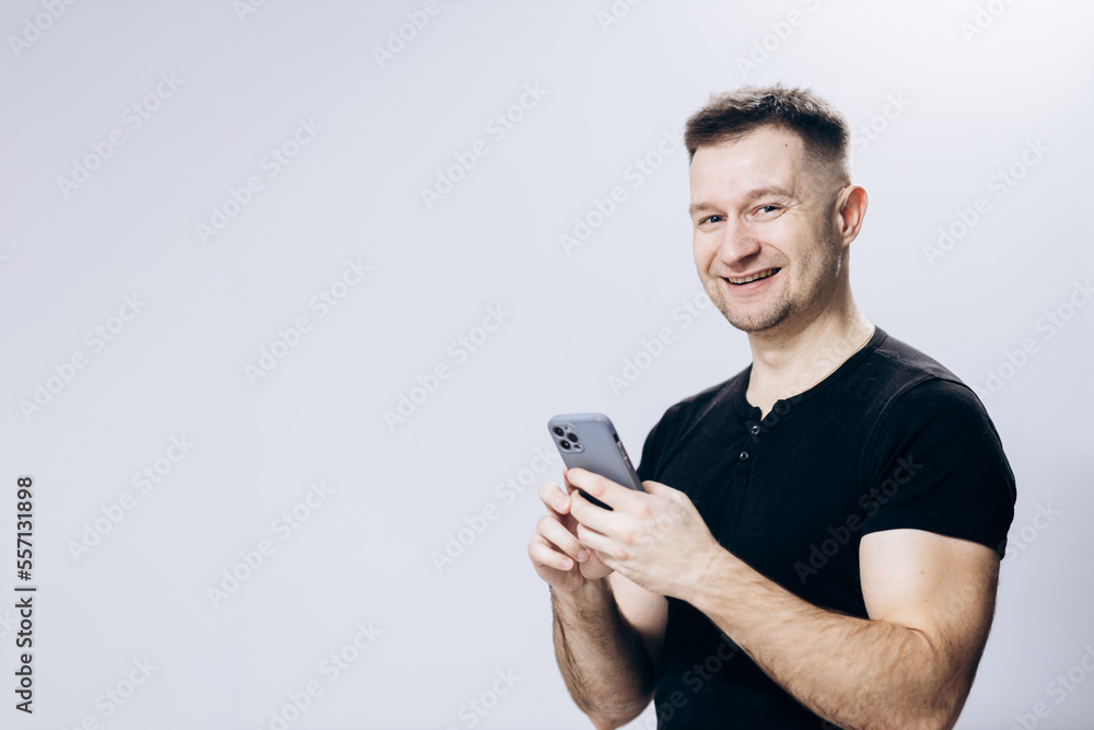 Confident man in a black t-shirt posing for the camera. The boss is holding a phone in his hand Confident man in a black t-shirt posing for the camera. The boss is holding a phone in his hand
