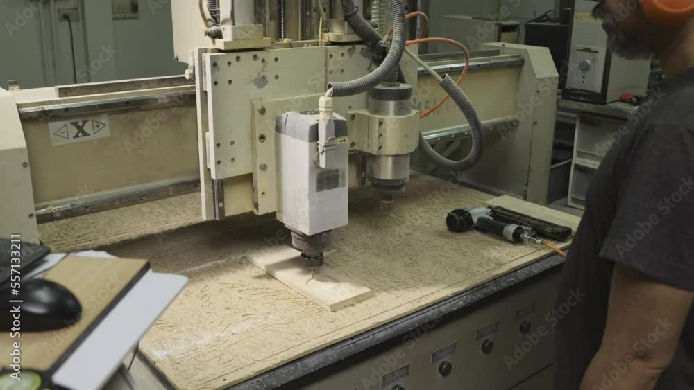 Senior man operate CNC machine to cutting wood products in factory.