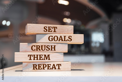 Wooden blocks with words 'Set goals crush them repeat'.