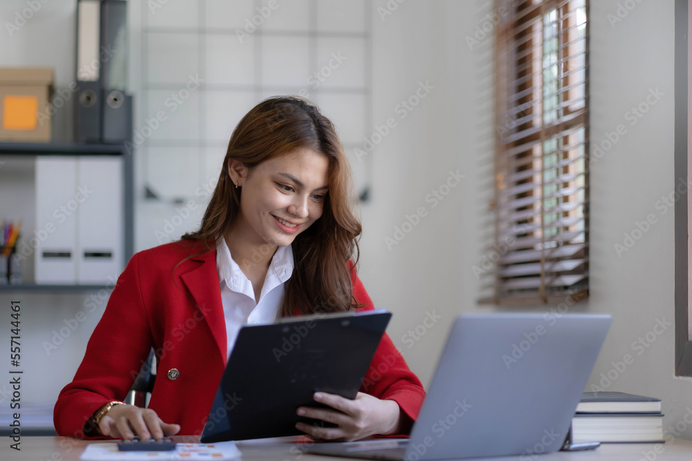 Asian Business woman using calculator and laptop for doing math finance on an office desk, tax, report, accounting, statistics, and analytical research concept Asian Business woman using calculator and laptop for doing math finance on an office desk, tax, report, accounting, statistics, and analytical research concept
