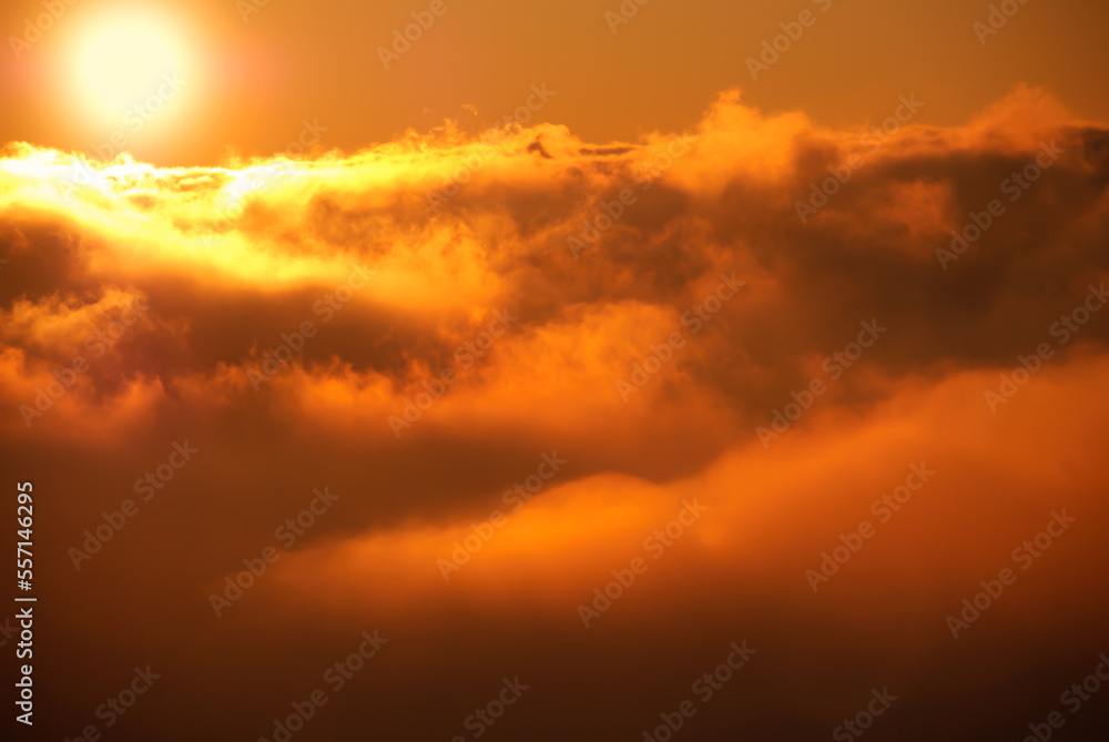 Beautiful sunset / sunrise cloudy sky from aerial view with gentle colorful clouds and dramatic light. Airplane view above clouds. Vivid twilight sky painted by the sun leaving bright golden shades