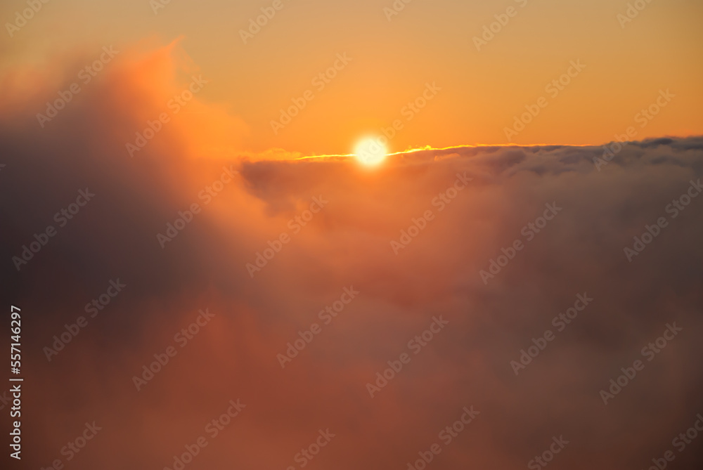 Fototapeta premium Beautiful sunset / sunrise cloudy sky from aerial view with gentle colorful clouds and dramatic light. Airplane view above clouds. Vivid twilight sky painted by the sun leaving bright golden shades