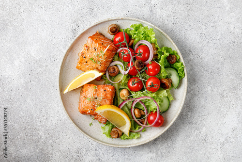 Salmon with green fresh vegetable salad, tomatoes cherry, onion on ceramic plate. Concept keto diet healthy food. Dinner idea.