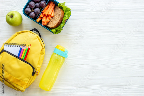 Photography Healthy school lunch box with fruits and backpack, top view