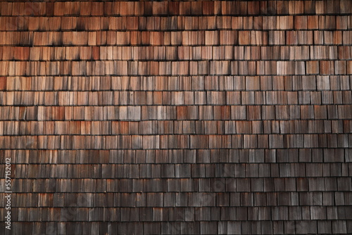 a house wall covered with small wooden tiles as a background  photo