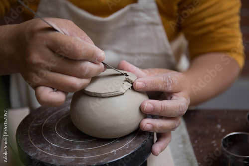 Close up hand of Asian Female using pottery wheel to make a tea pot in the workshop