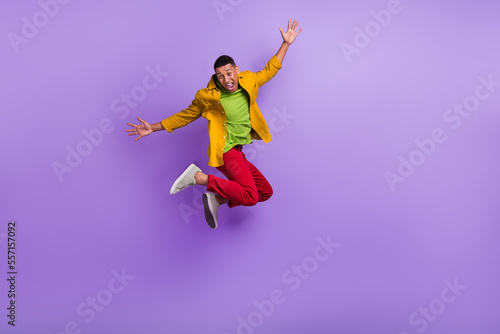 Full body photo of active overjoyed person jumping raise hands isolated on violet color background © deagreez